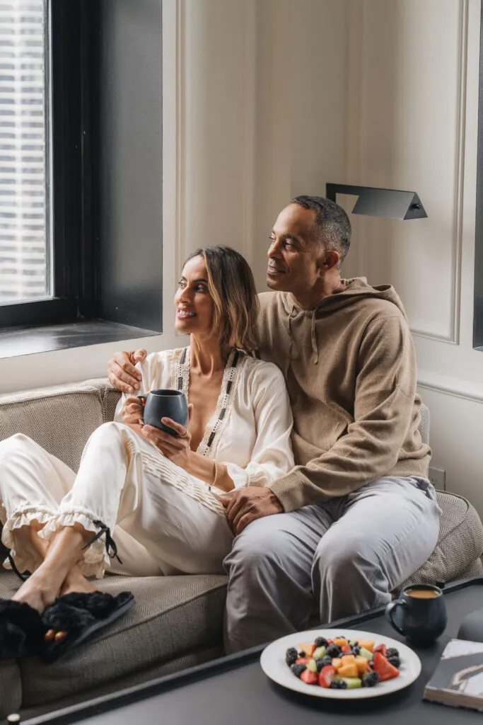 A couple sitting on a couch in their guestroom at Pendry Chicago