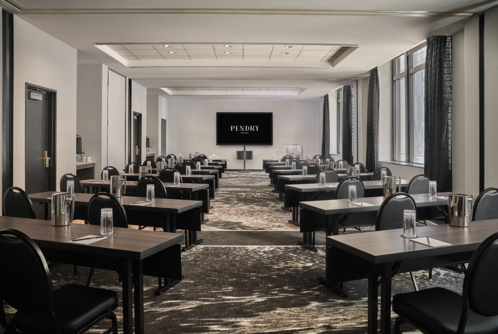 Conference room with rows of tables and chairs facing a screen.
