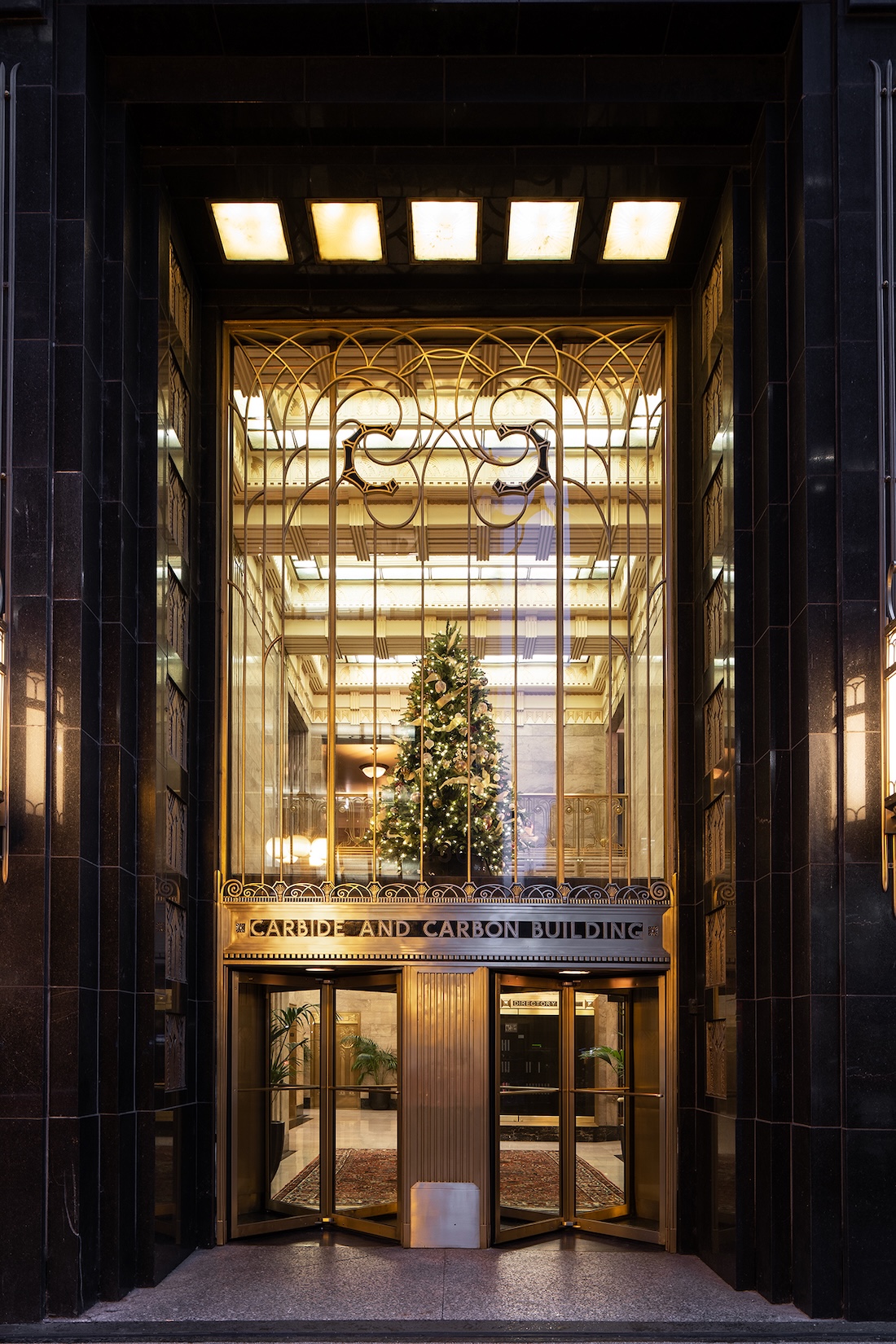 Holiday-decorated building entrance with a Christmas tree