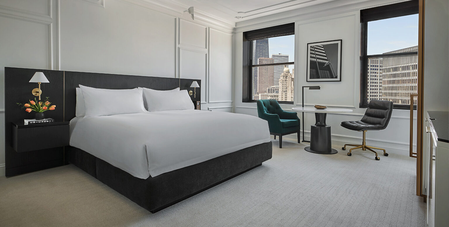 A king bed overlooking the Chicago skyline in a guestroom at Pendry Chicago