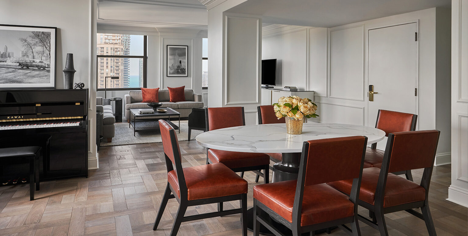 A dining table next to a piano in the Pendry Suite at Pendry Chicago