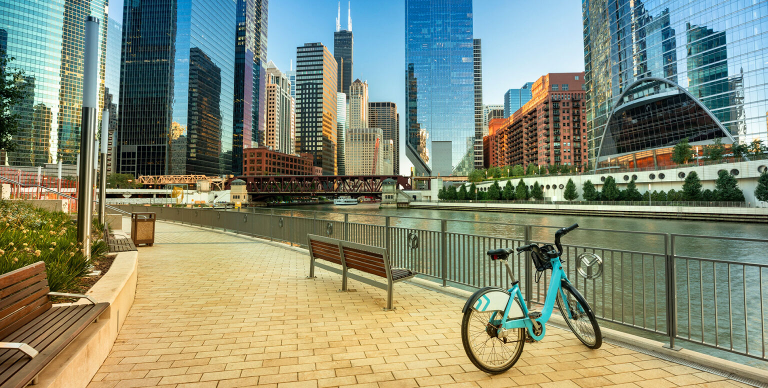 A bike perched up on a fence next to the Chicago River