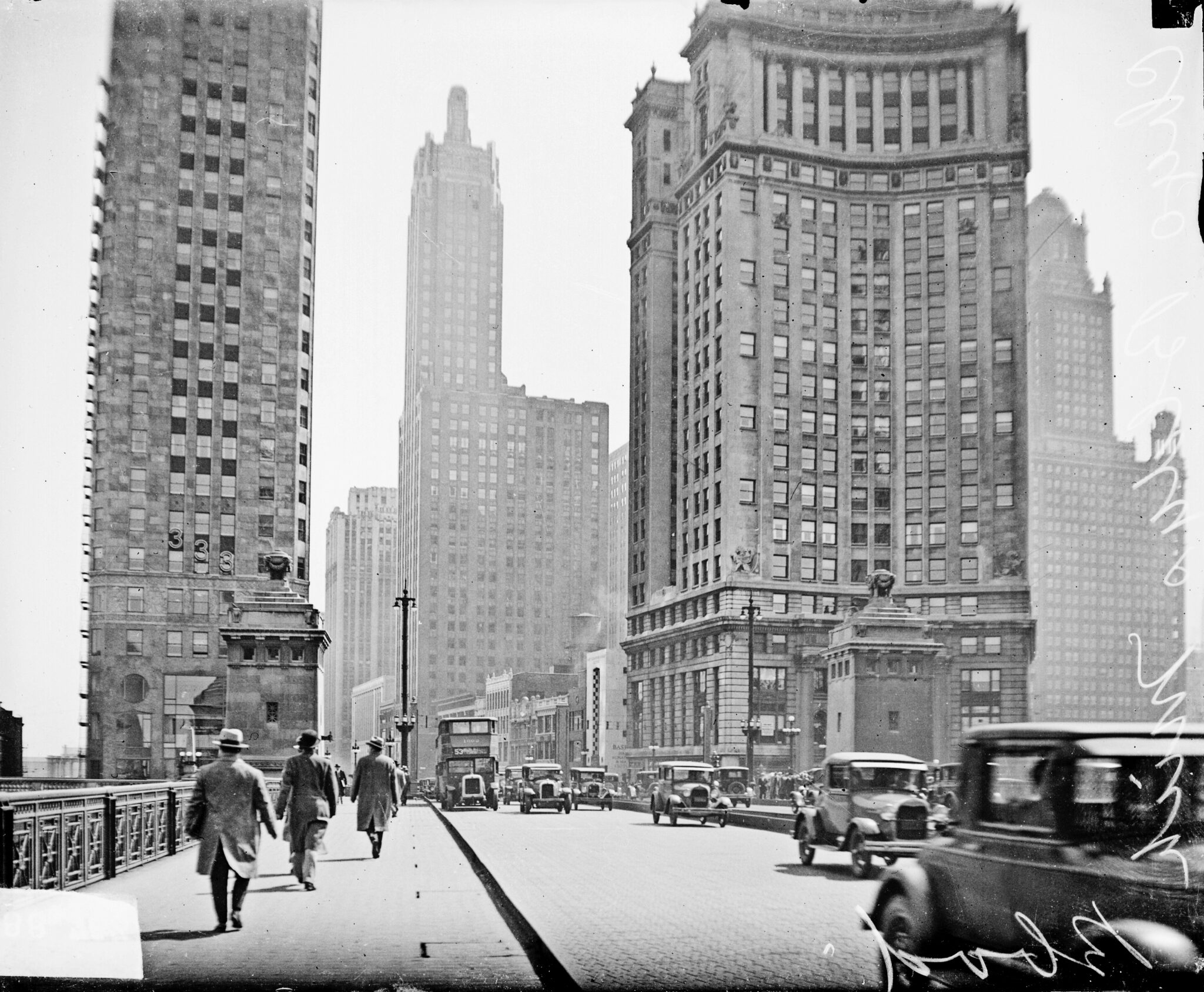 View of skyscrapers along Michigan Avenue where pedestrians are walking and cars are driving in the foreground, dark exposure