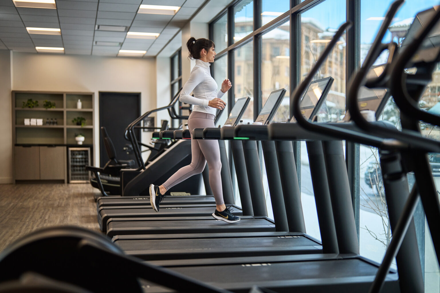 A woman running on a treadmill in Pendry Park City's fitness center