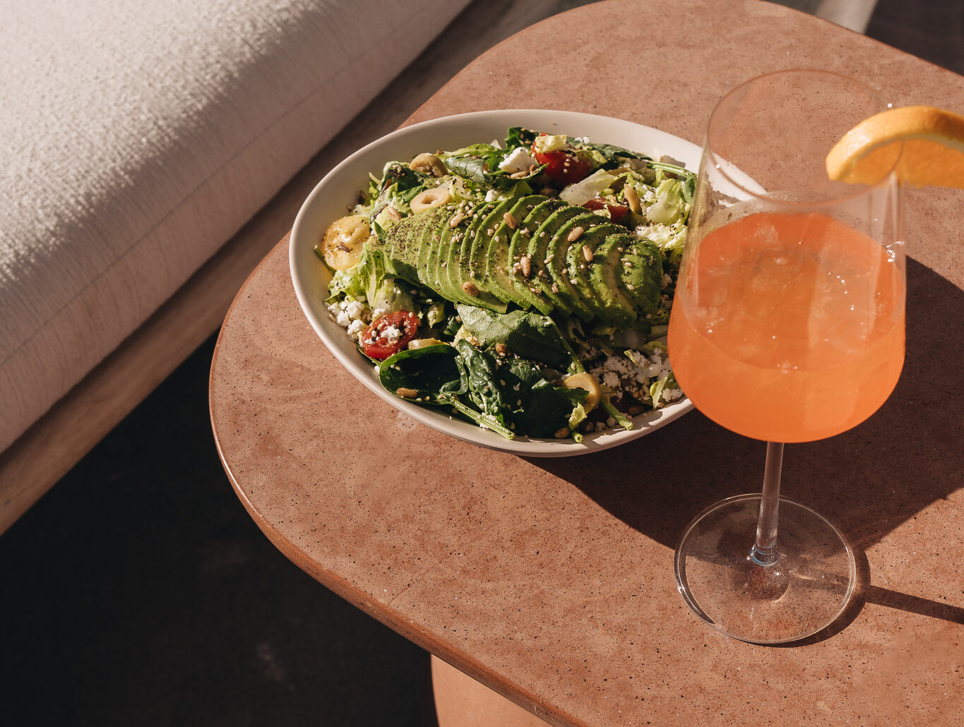 green salad on a table with an aperol spirtz