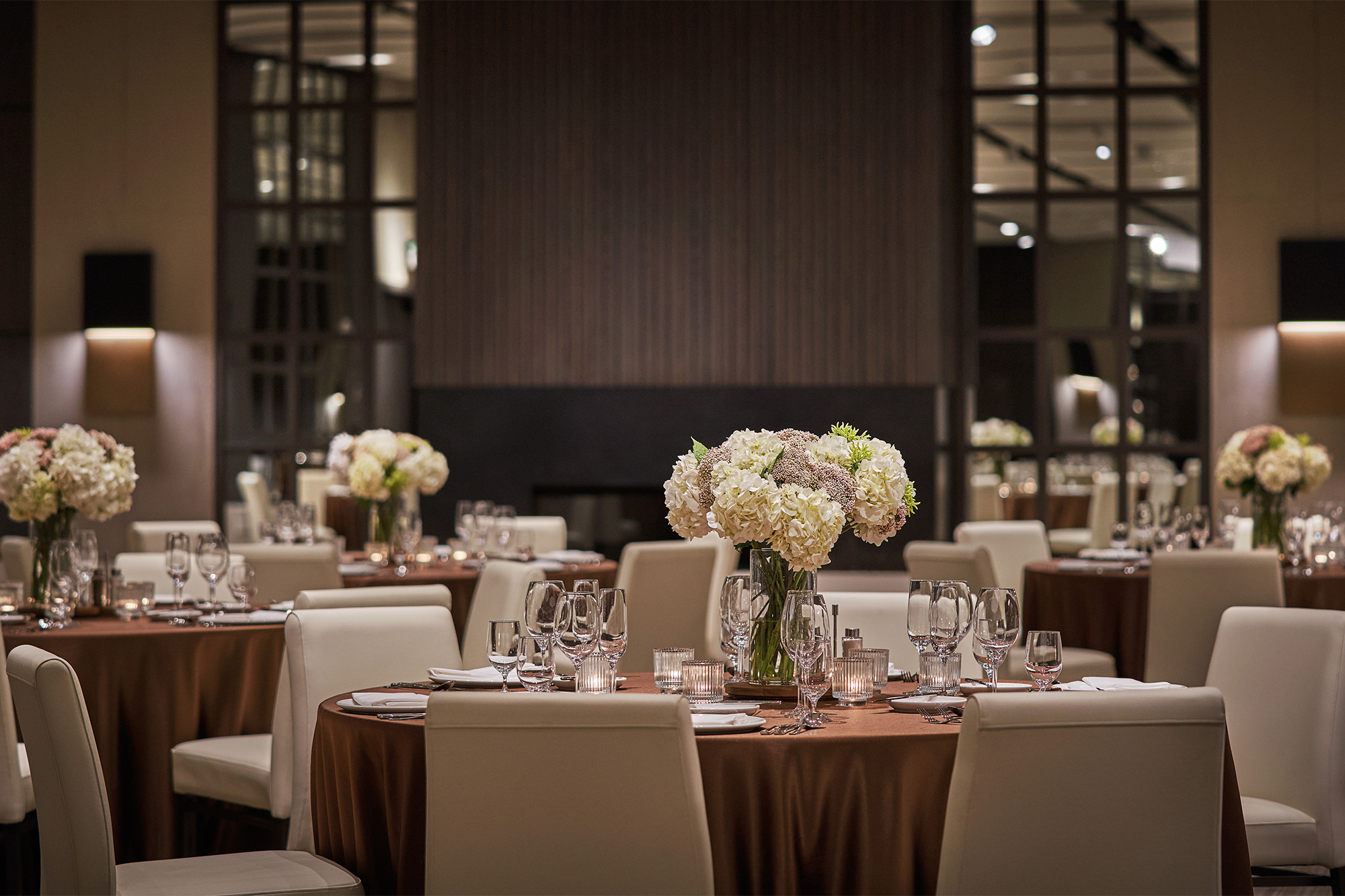 Junior Ballroom at Pendry Park City with round tables, white chairs, floral centerpieces, and soft lighting.