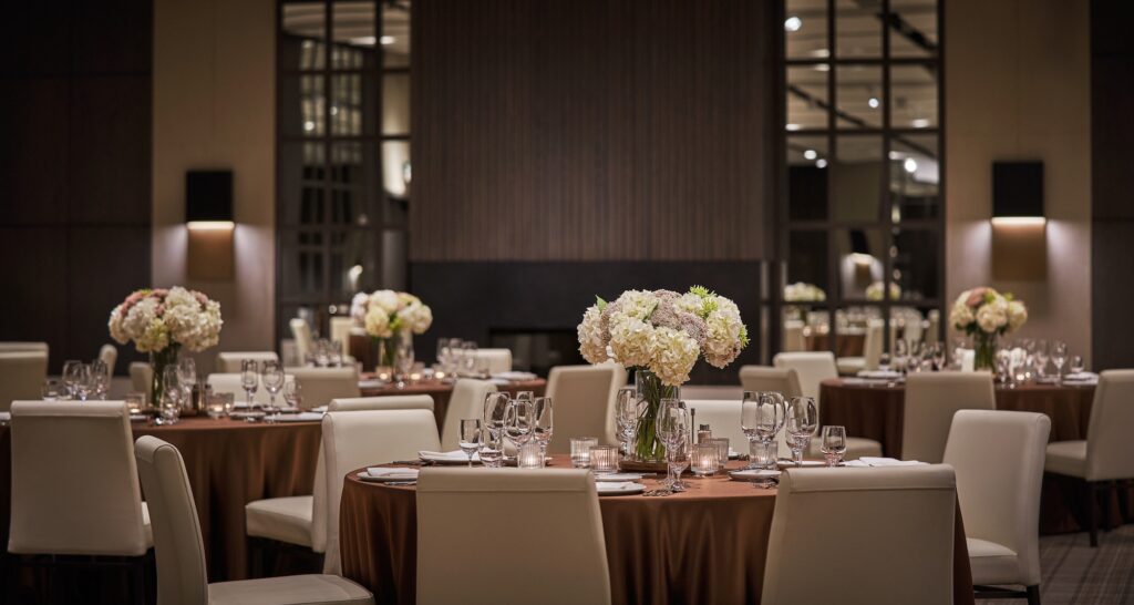 Banquet hall with round tables, white chairs, floral centerpieces, and soft lighting