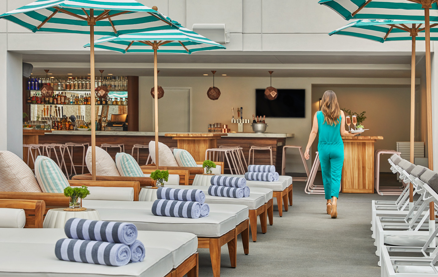A waitress carrying drinks at the pool restaurant at Pendry San Diego