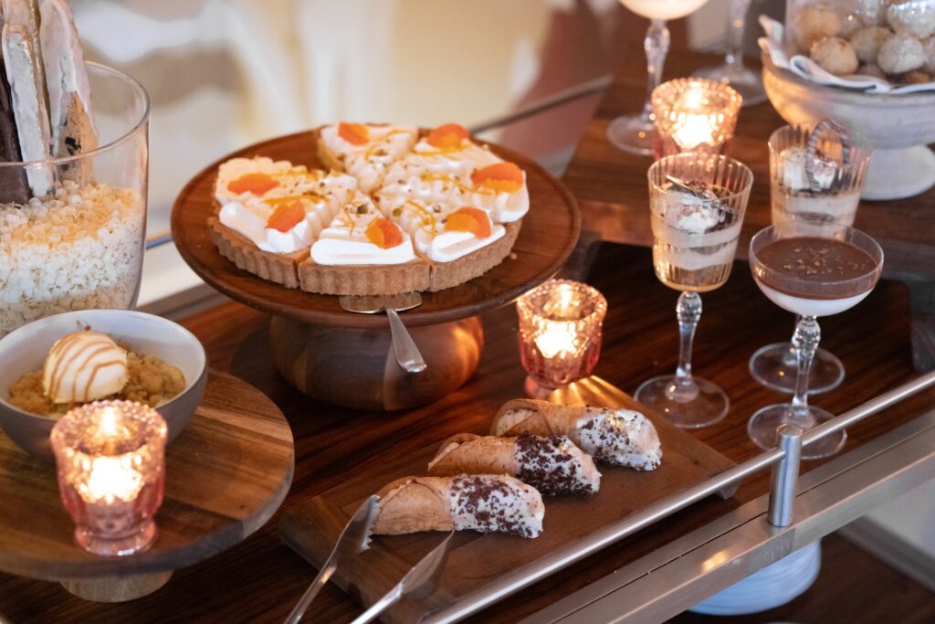 Assorted desserts on display, including tarts, cannoli, parfaits, and candles