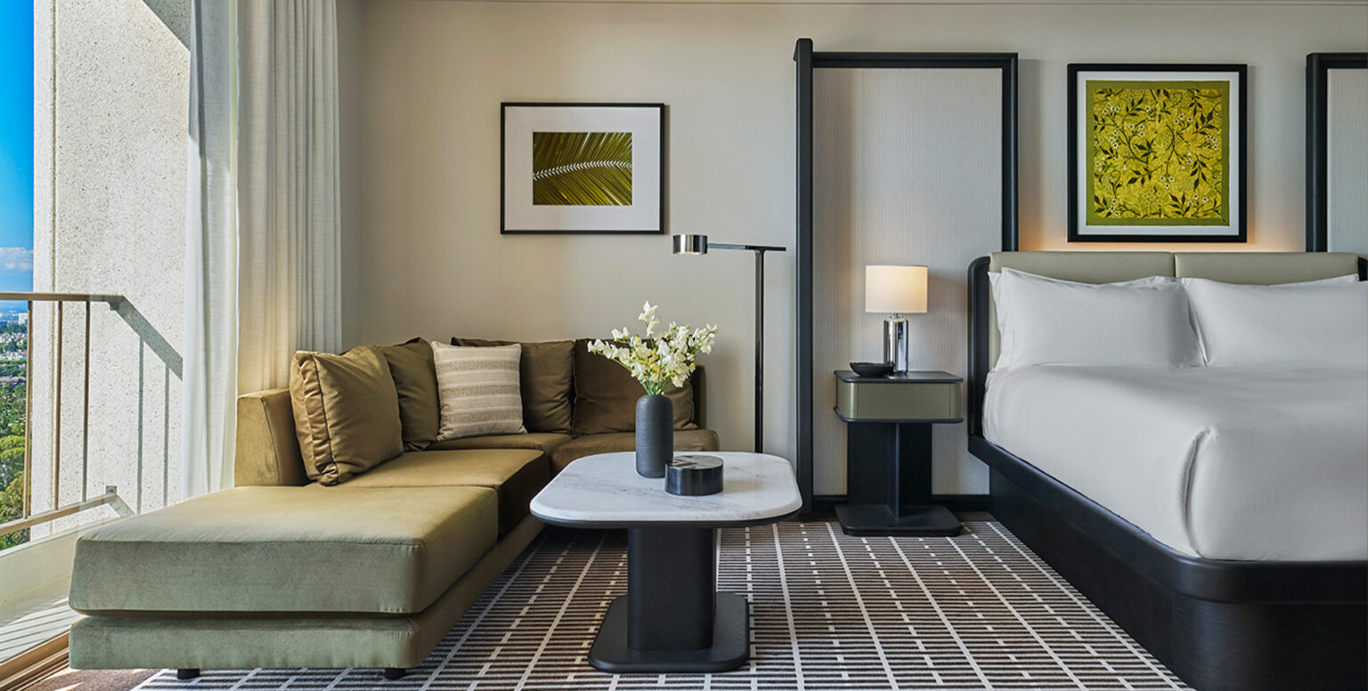 A couch and coffee table next to a king bed at Pendry Newport Beach
