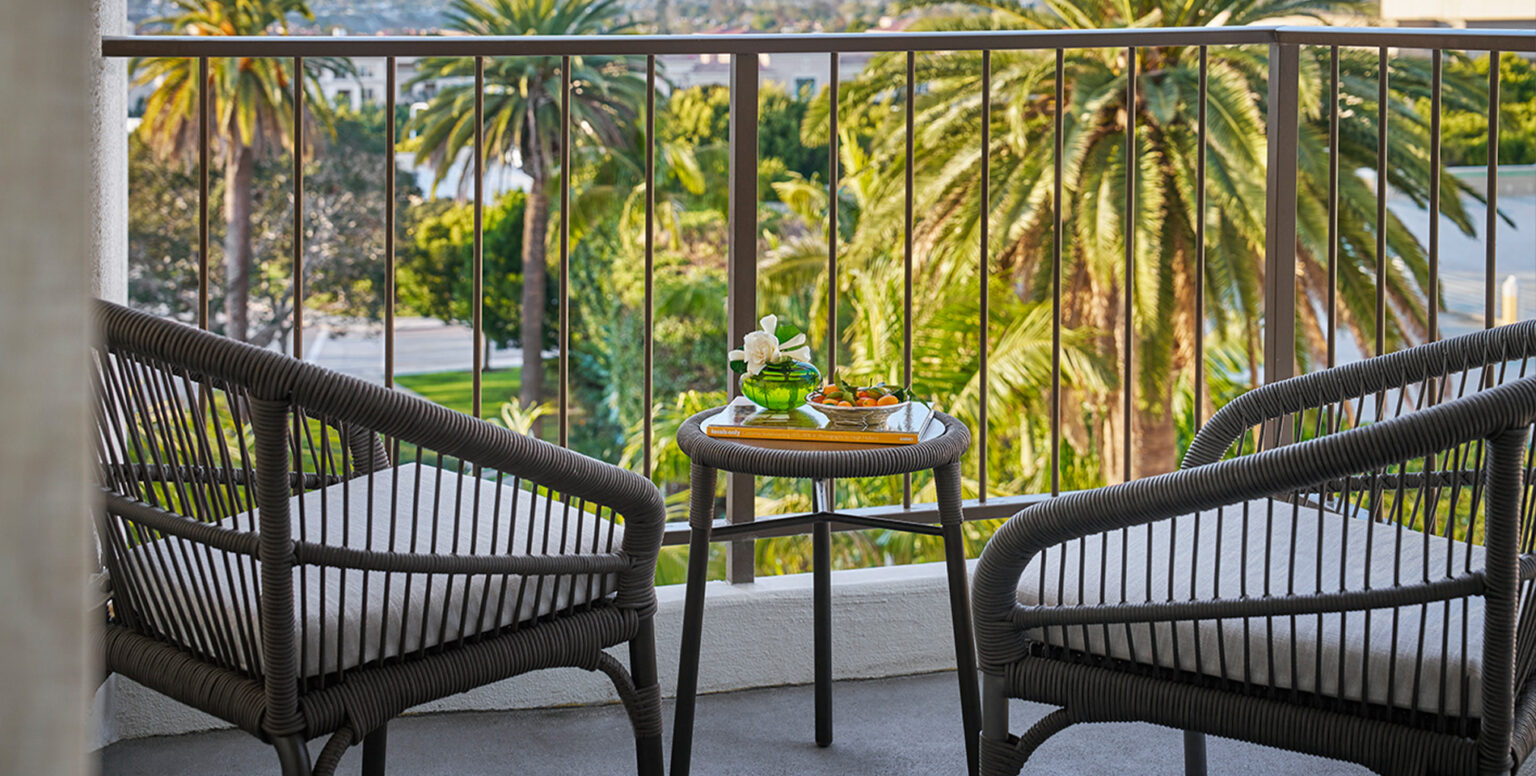 A balcony of a guestroom overlooking palm trees at Pendry Newport Beach resort