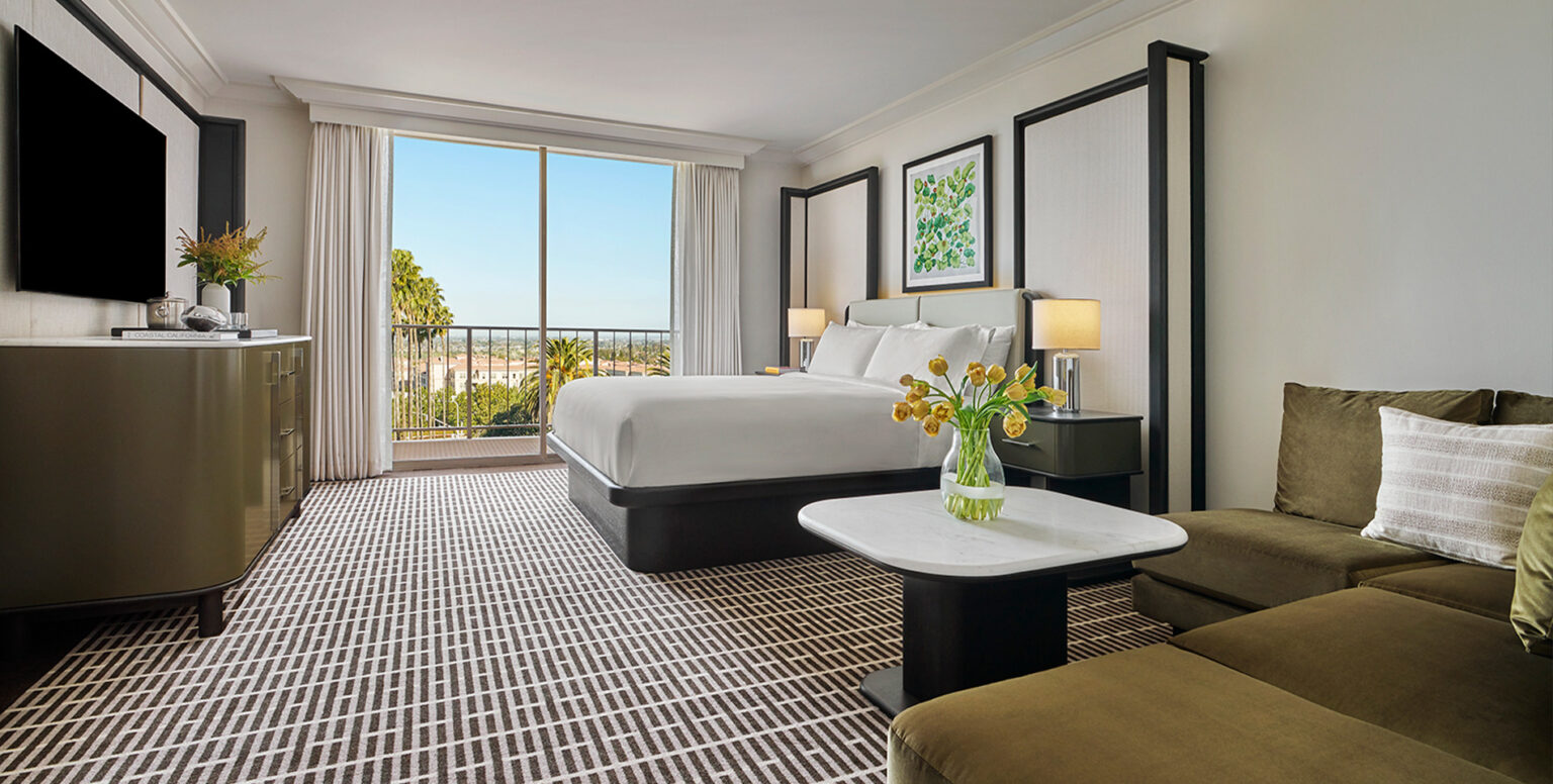 A king guestroom with a couch and coffee table overlooking Newport Beach
