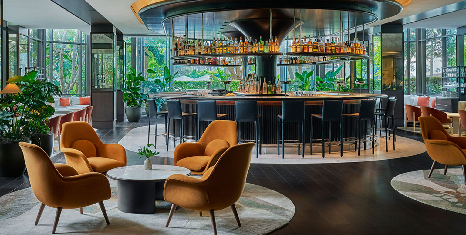 A circular bar with orange chairs and coffee tables around it at Bar Pendry Newport Beach