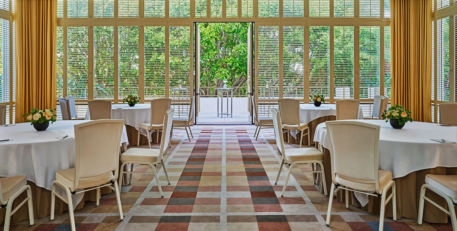 The Salon event room at Pendry Newport Beach with tables and chairs and an outdoor area