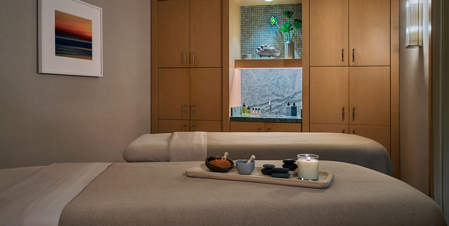 Two massage tables with rocks and herbs on them at Spa Pendry Newport Beach