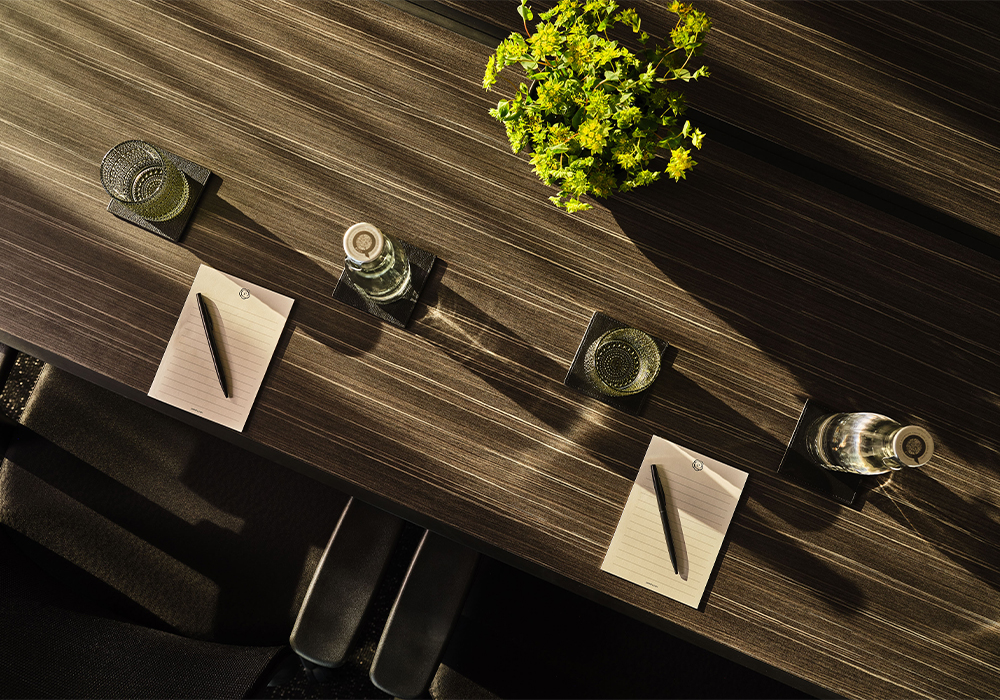 A wooden table with notepads and water cups on it