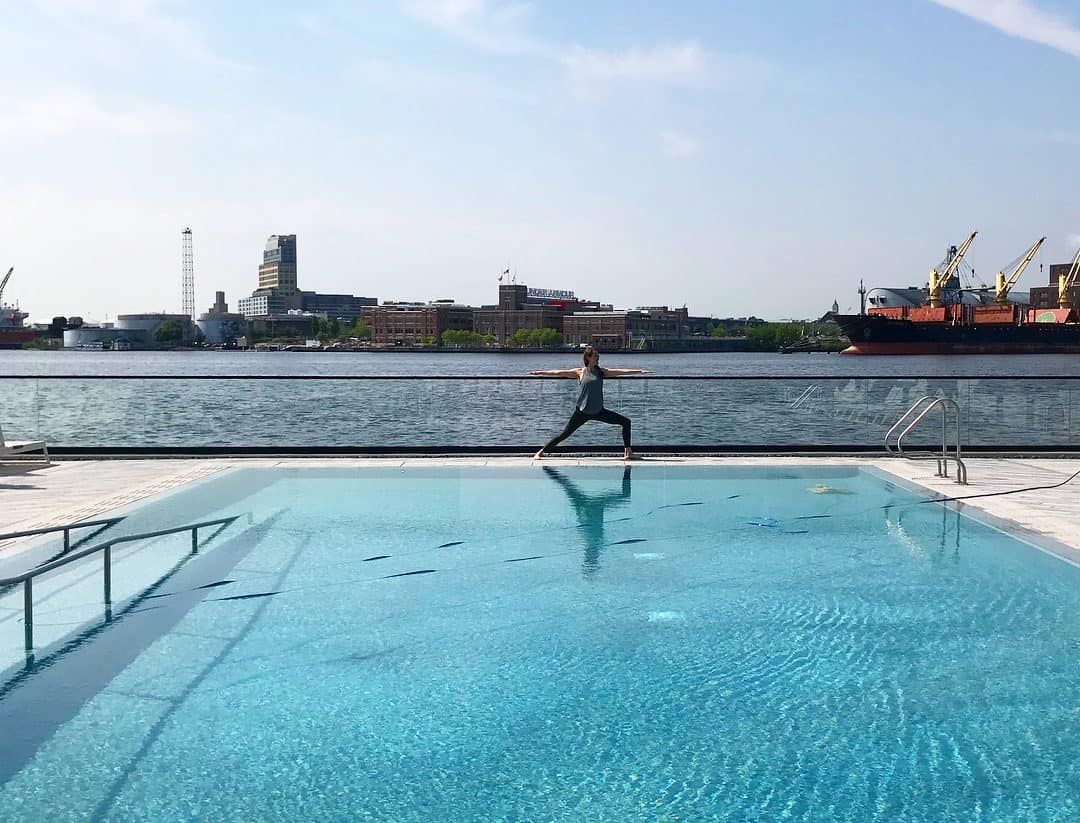 Woman doing yoga by the pool with views of the harbor