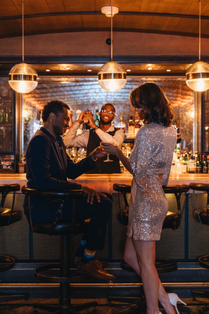Couple enjoying cocktails at a stylish bar with a smiling bartender