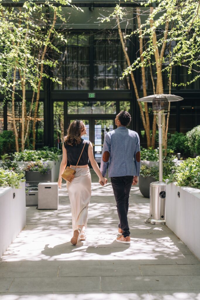 Couple walking hand in hand through a garden courtyard