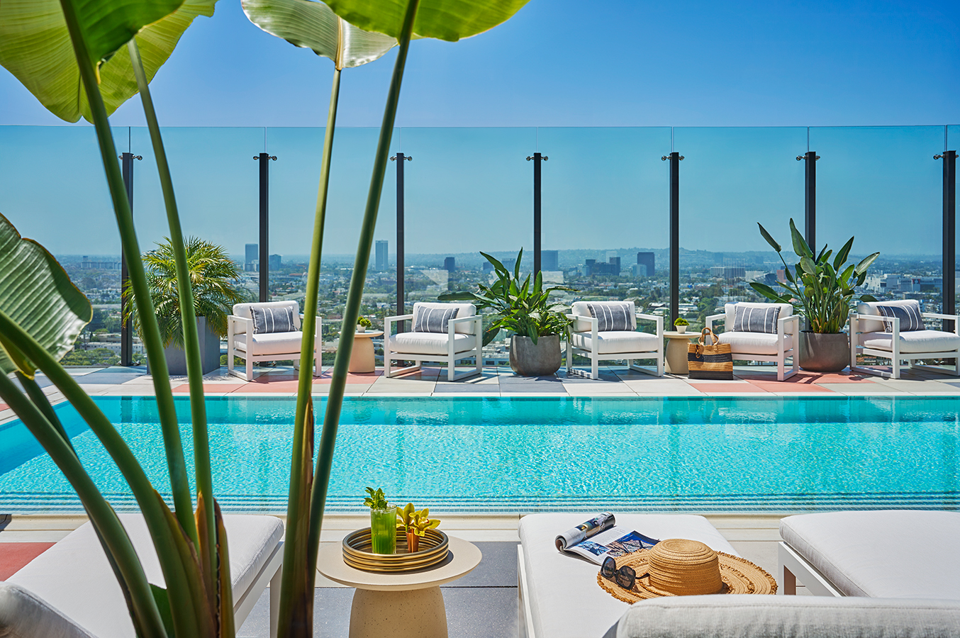 Close up view of pool chairs and beverage with a view of the pool at Pendry West Hollywood, a luxury boutique hotel on Sunset Boulevard