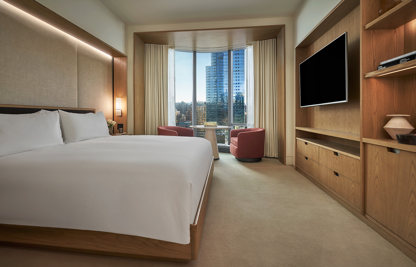 A bed, tv, and dresser in a guestroom at Pendry Manhattan West.
