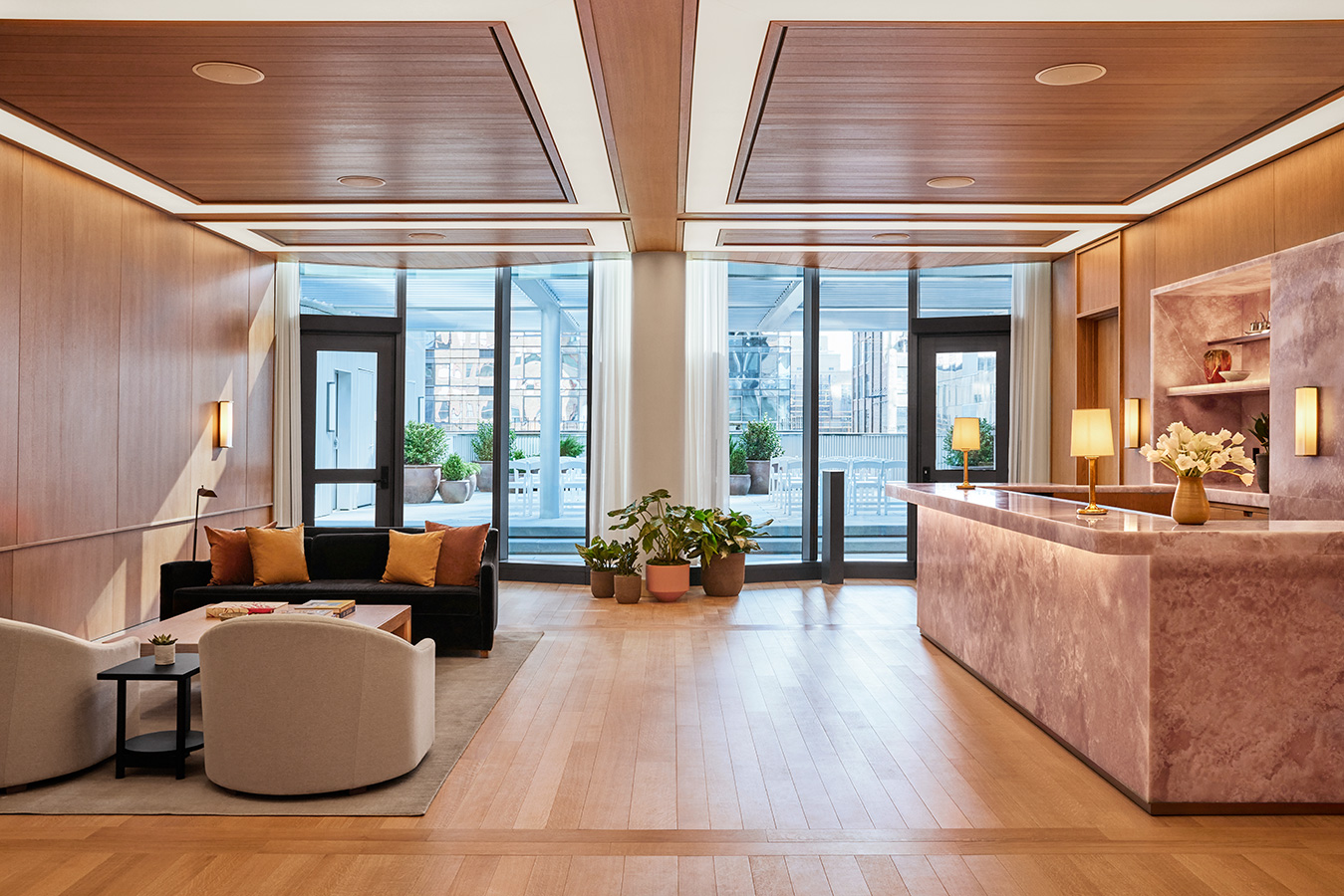 The Salon at Pendry Manhattan West featuring a marble bar, modern seating area, large windows and natural light.