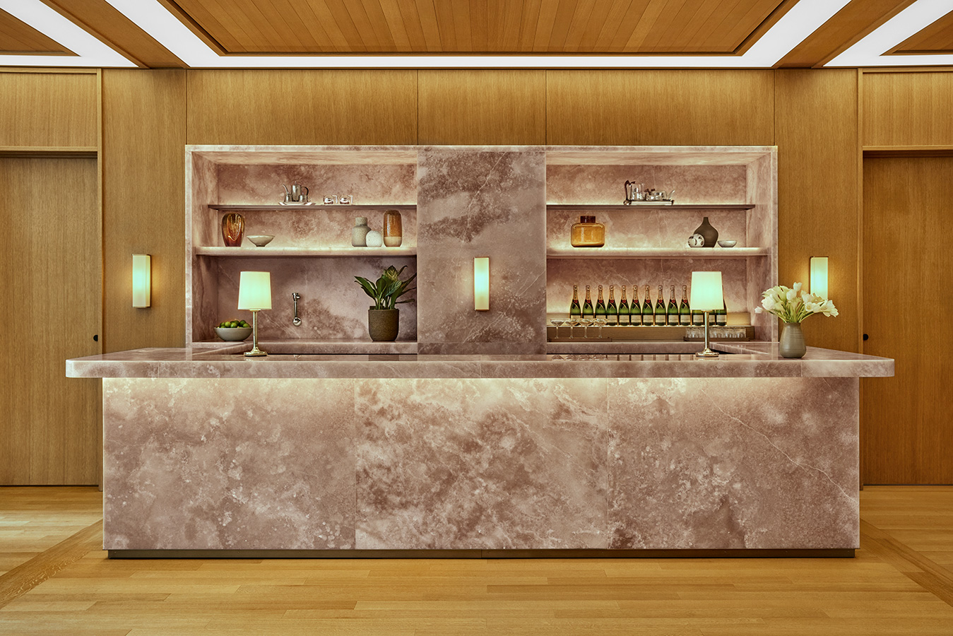 Marble bar at The Salon with backlit shelving, soft lighting and champagne bottles on display at Pendry Manhattan West.