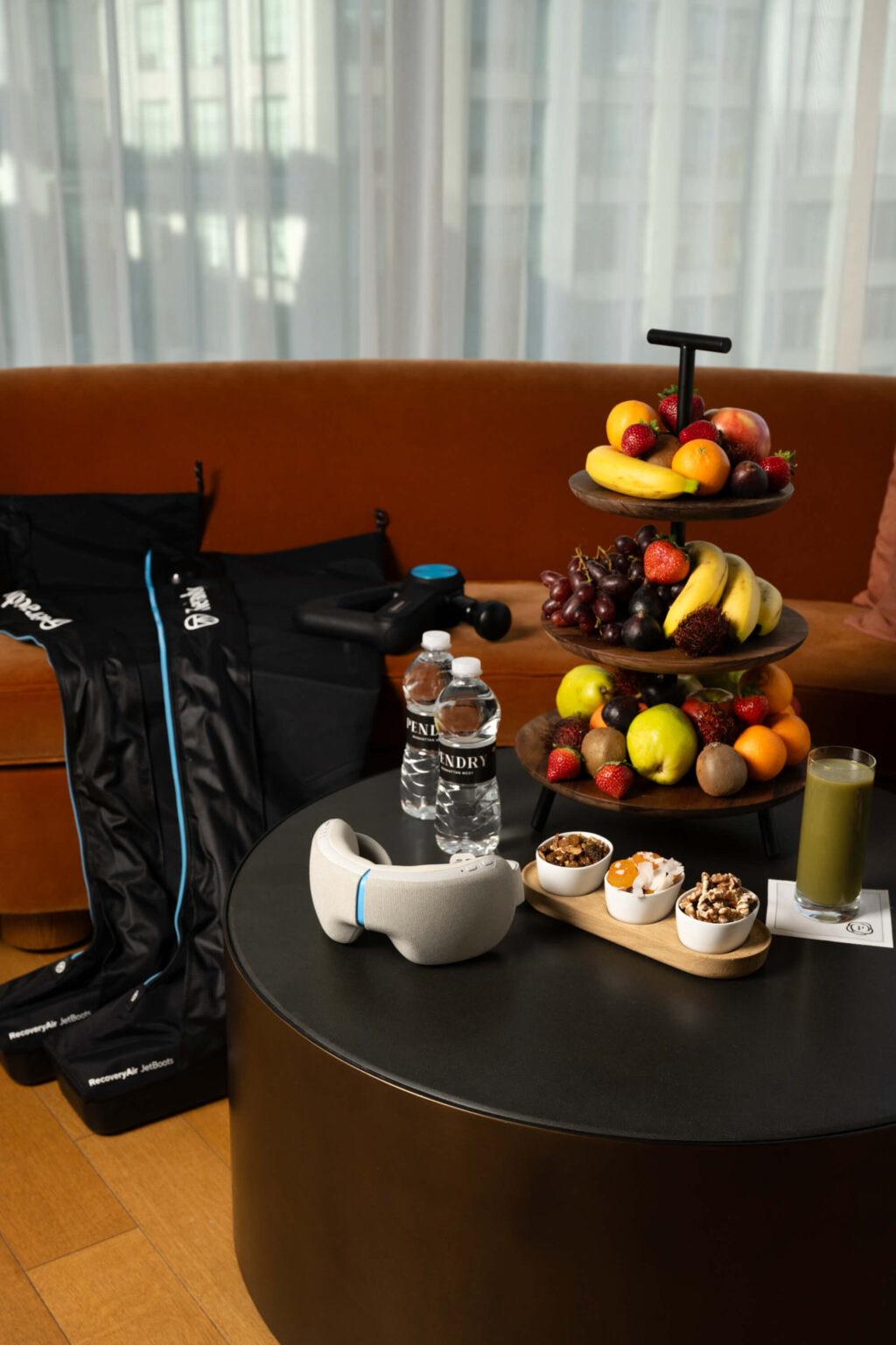 In-room wellness setup at Pendry Manhattan West with Therabody equipment, bottled water and fresh fruit.