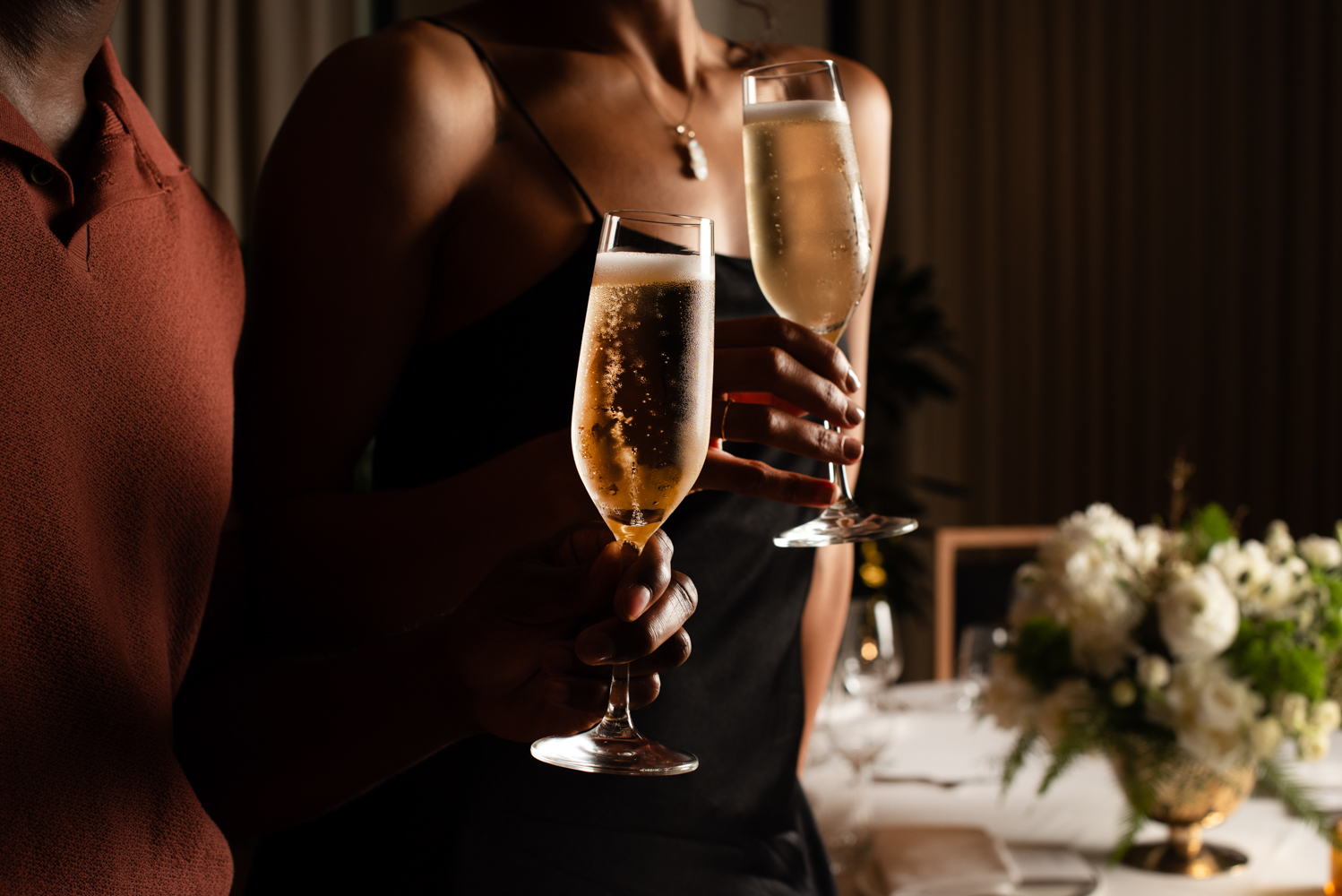 A couple holds champagne glasses at an elegant event