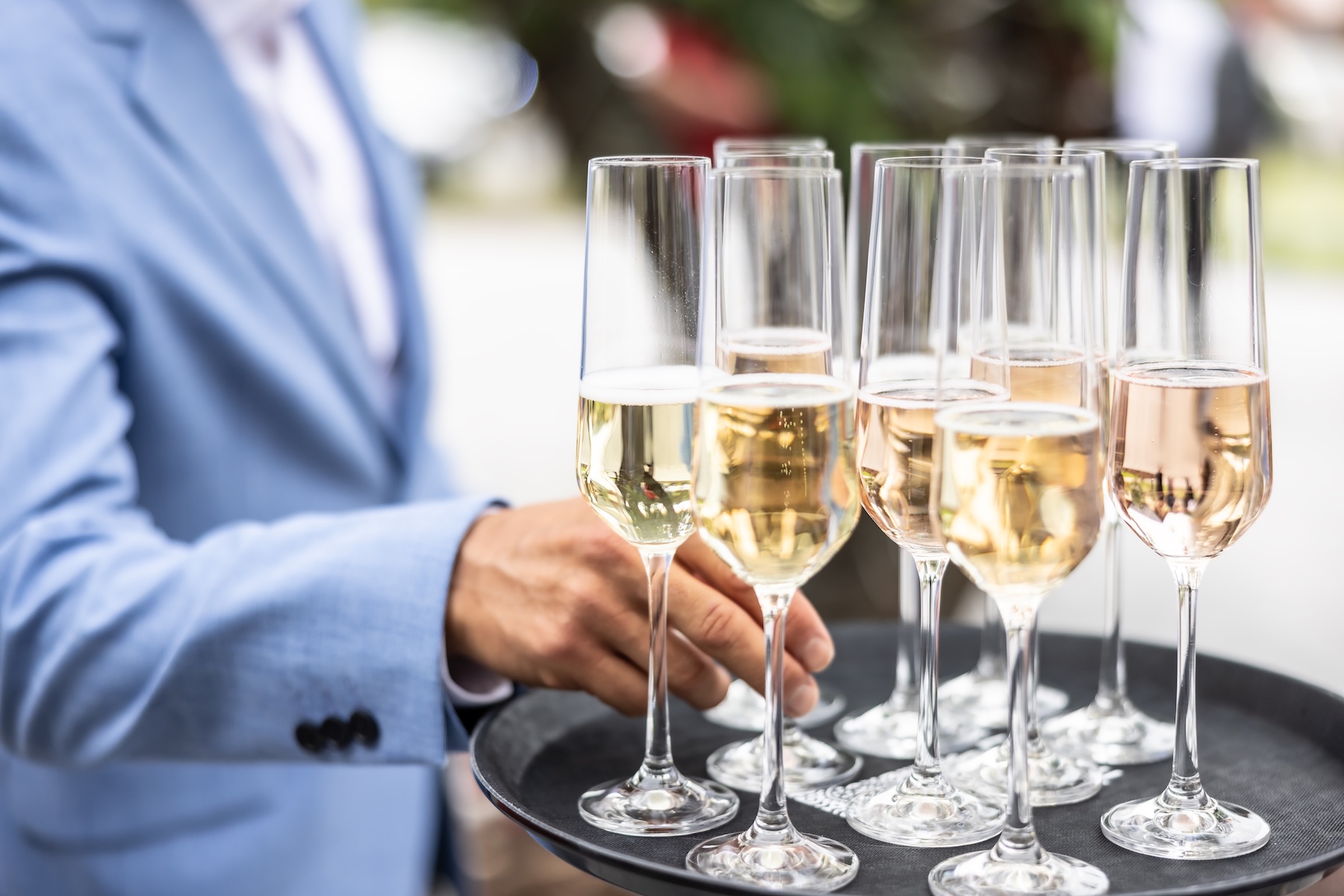 Tray of champagne and sparkling wine glasses being served at an event