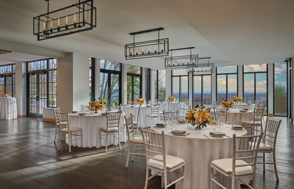 Elegant ballroom set with round tables, white linens, and floral décor at a wedding venue near NYC.