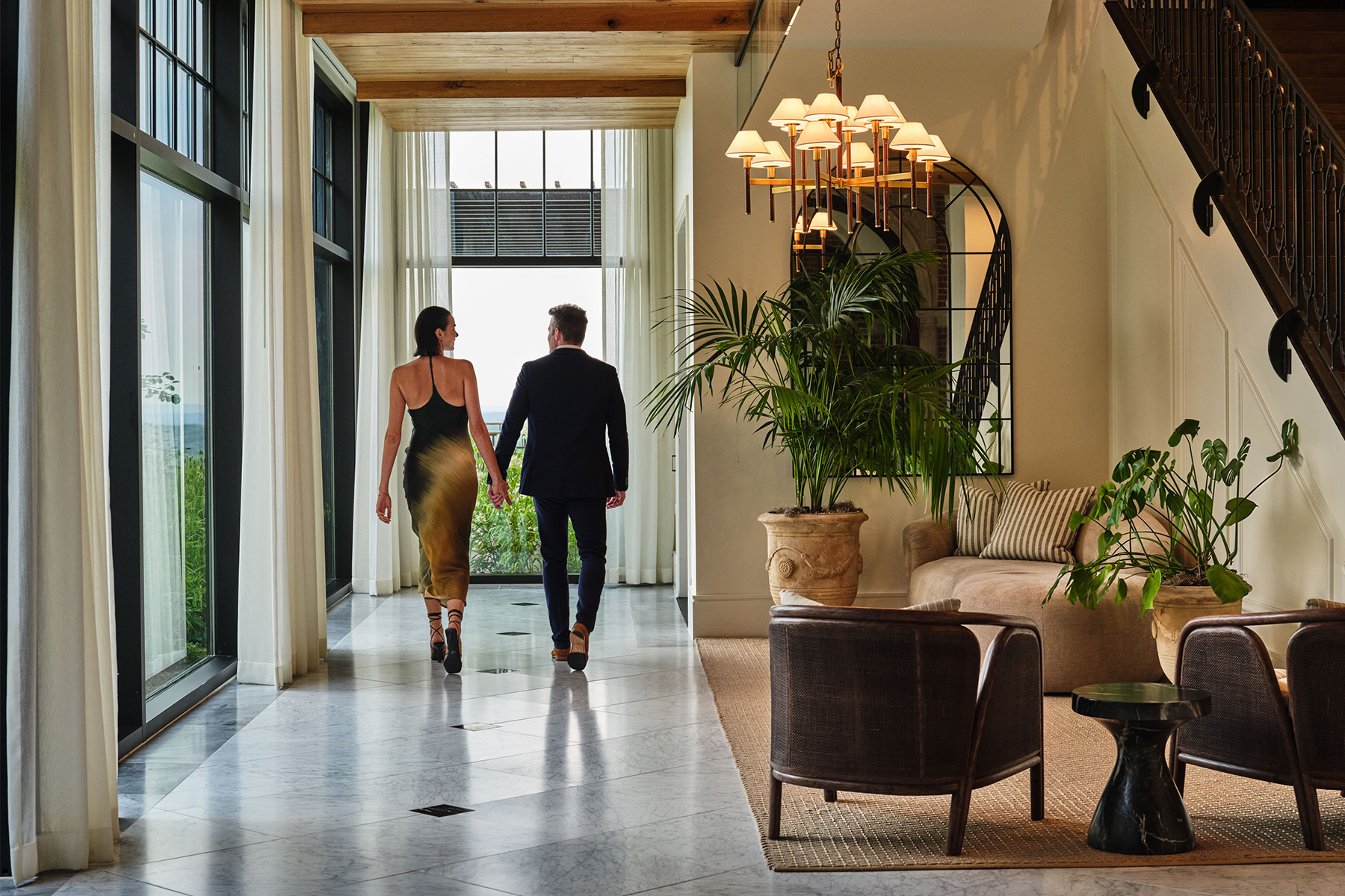 Couple holding hands and walking a hallway at Pendry Natirar.