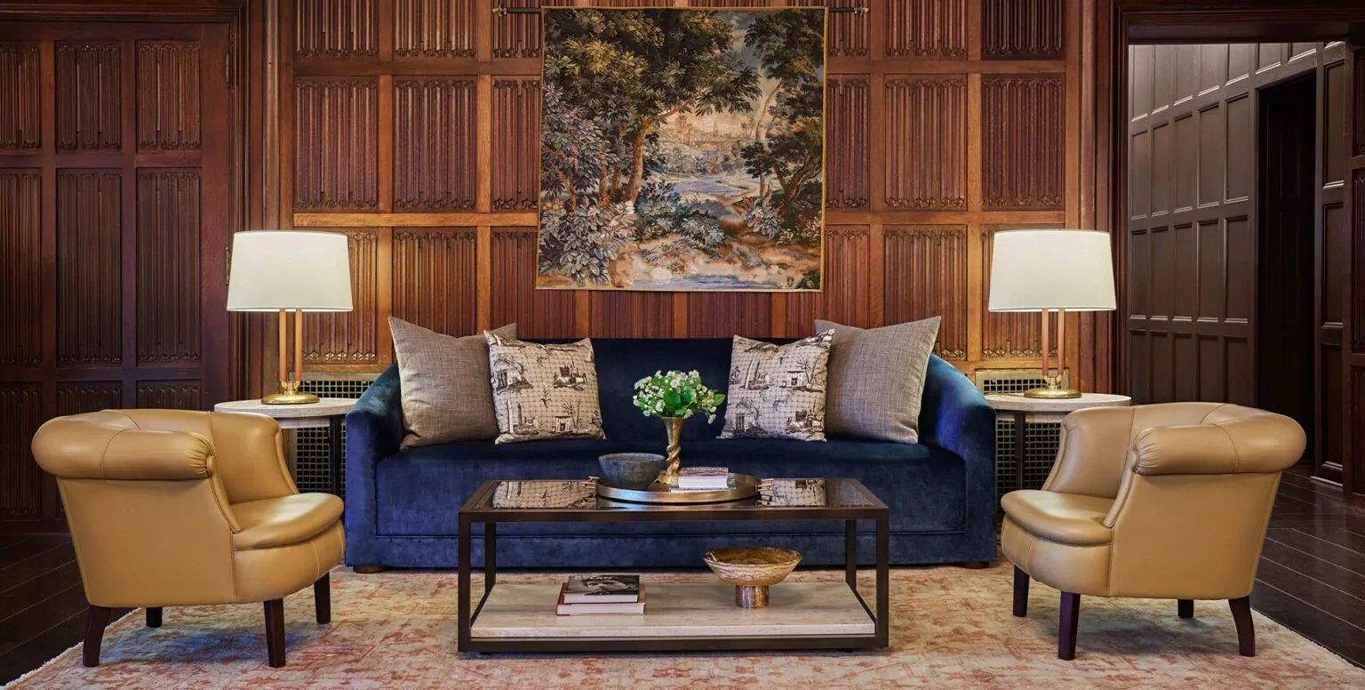 A blue couch with two yellow chairs beside it in the Great Room at Pendry Natirar