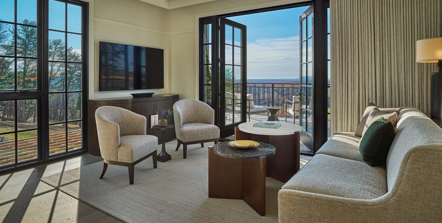 The living room of a suite with a balcony overlooking Natirar