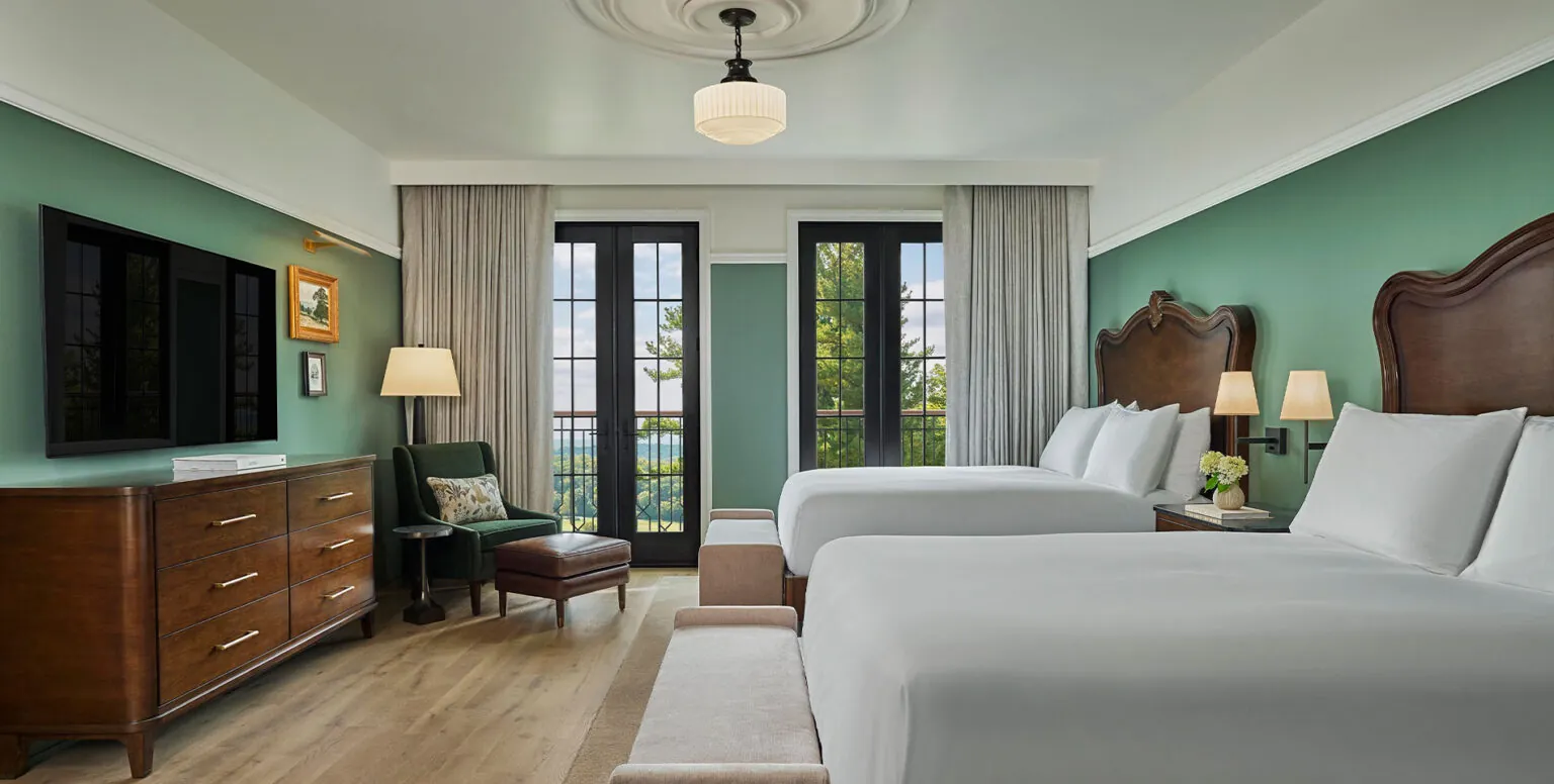 Two queen beds in a guestroom at Pendry Natirar with two floor to ceiling french doors