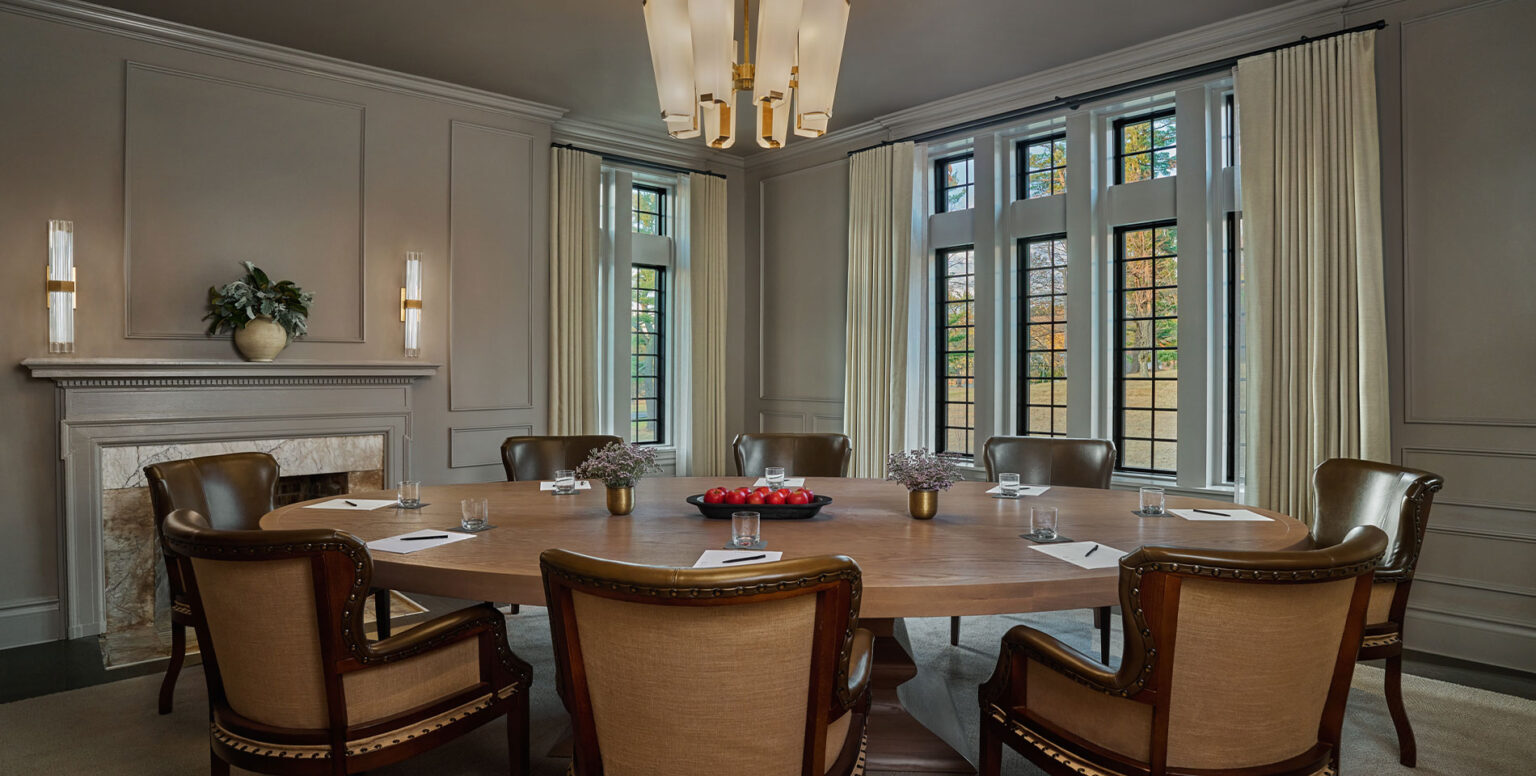 A meeting room in Somerset County with a wooden round table and rustic chairs at Pendry Natirar