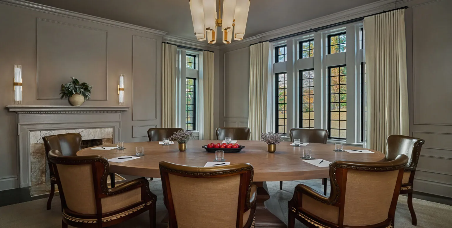A meeting room in Somerset County with a wooden round table and rustic chairs at Pendry Natirar