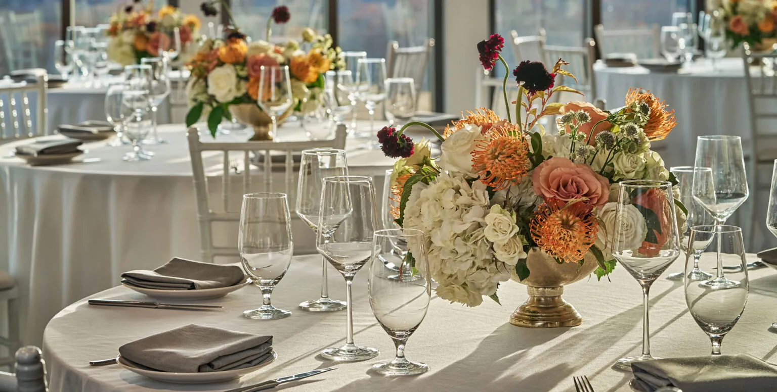 A close up of a wedding reception table with a floral center piece and wine glasses at Pendry Natirar