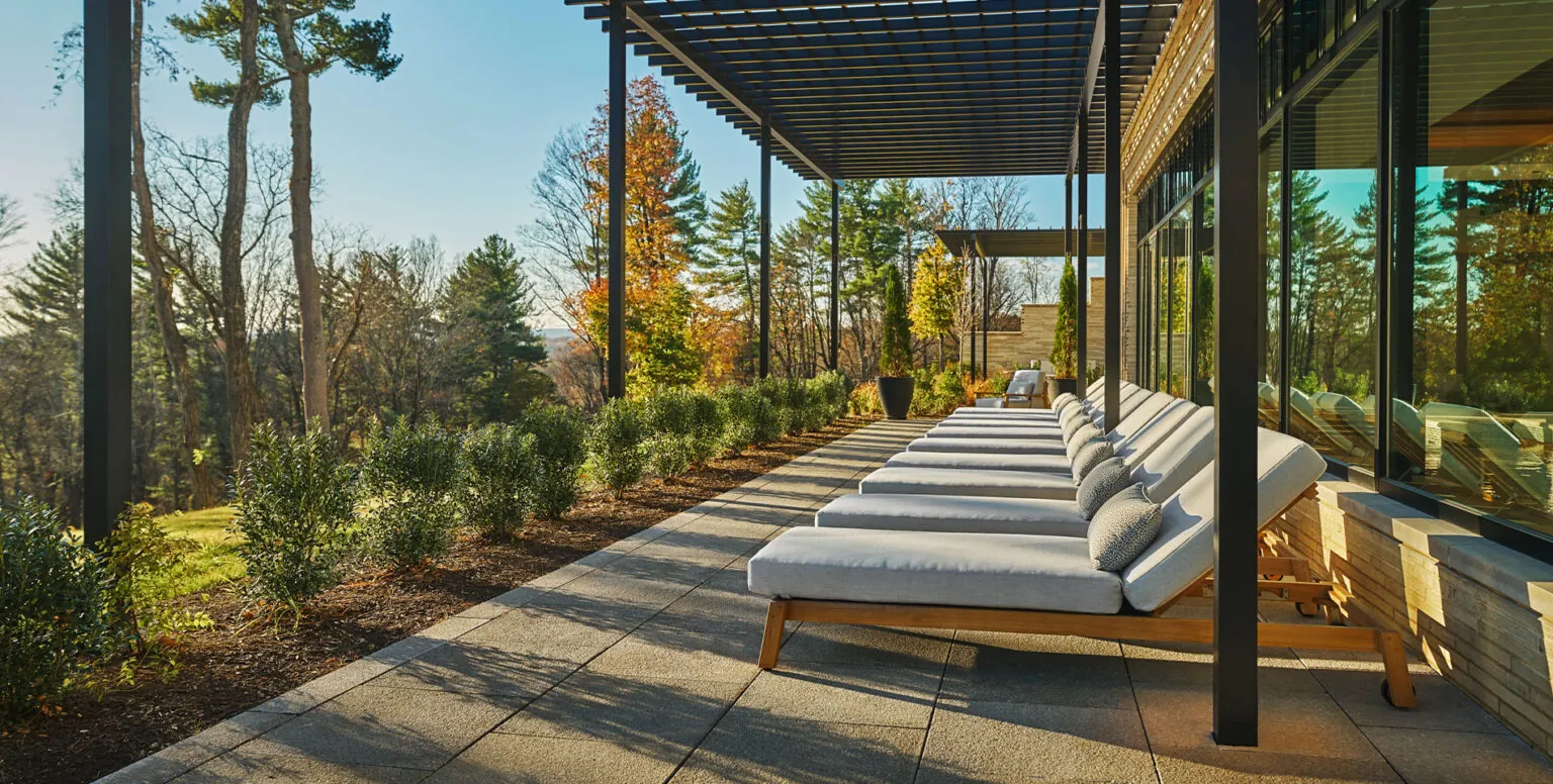 Daybeds lined up on a patio overlooking the Somerset valley at Pendry Natirar