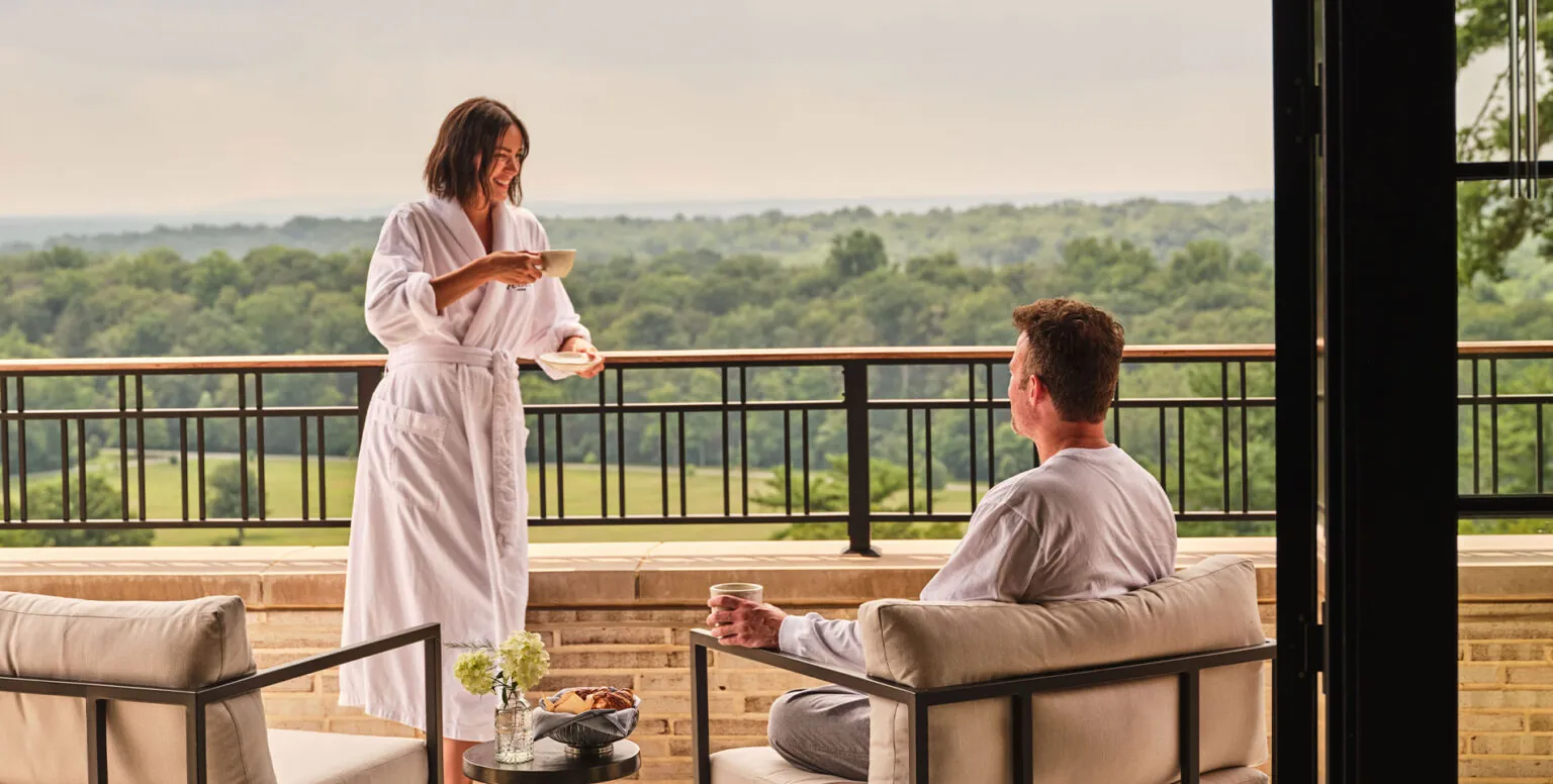 A couple having coffee on the balcony of their guestroom at Pendry Natirar