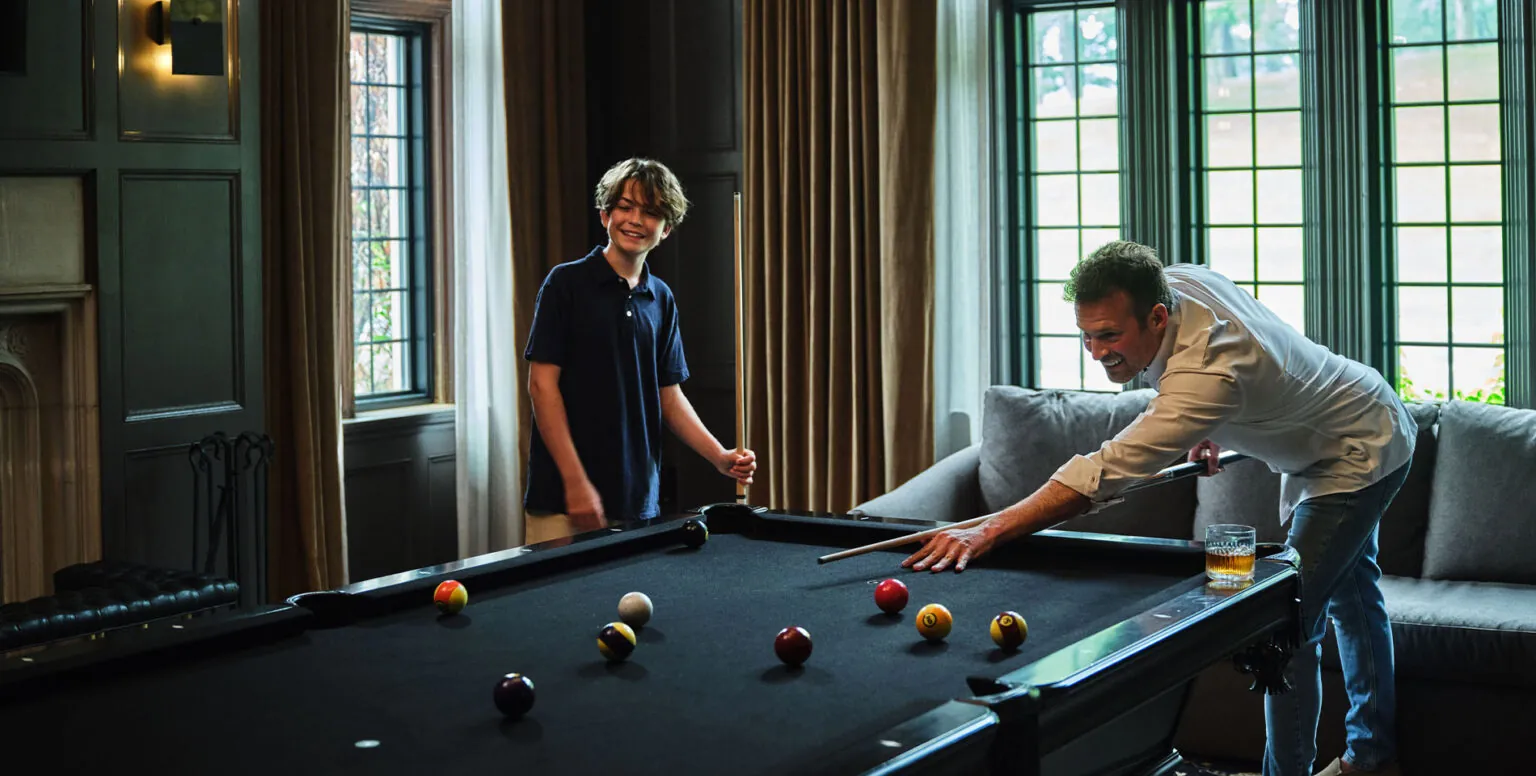 A father and son playing pool in a moody room at Pendry Natirar