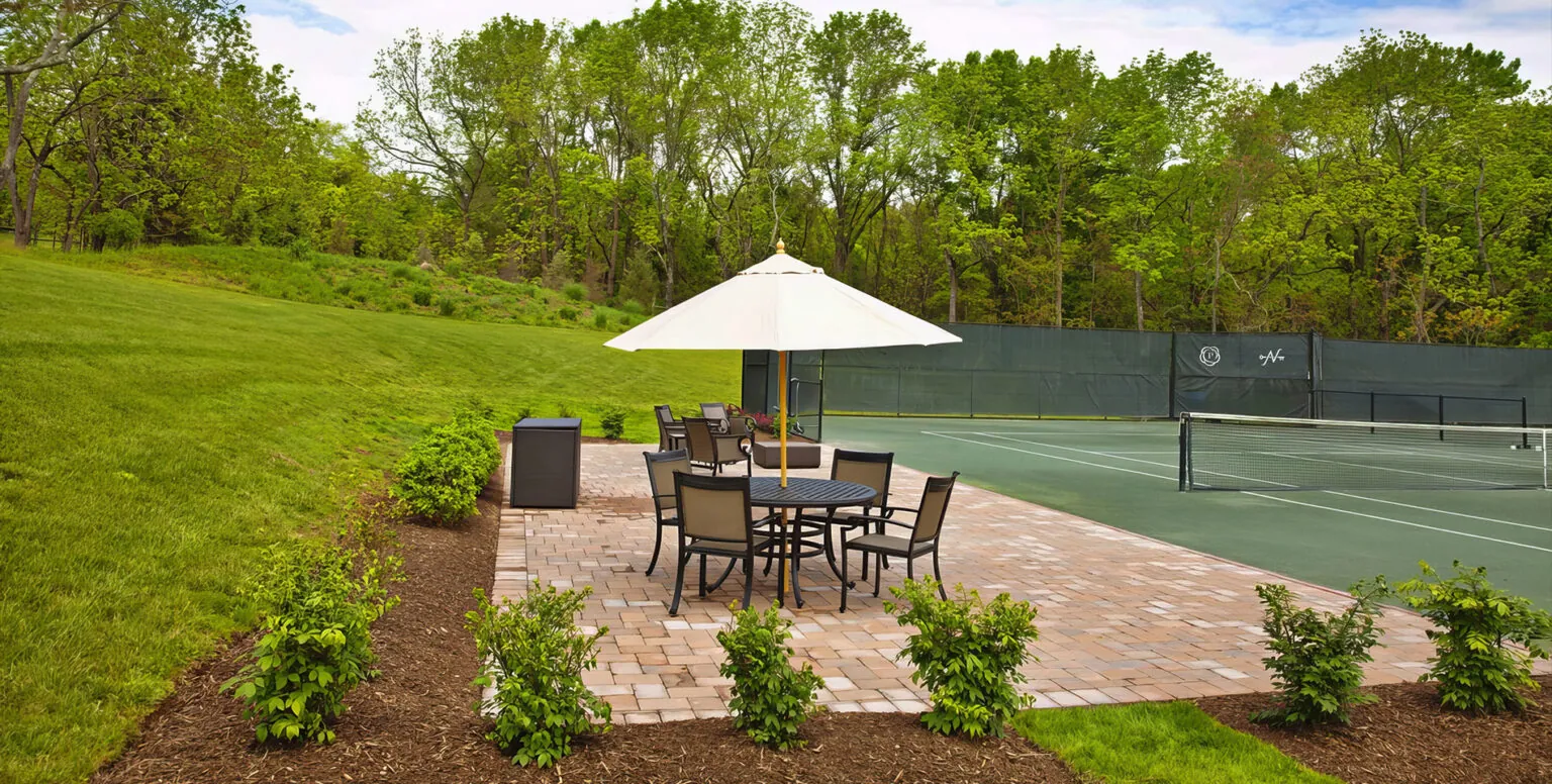 An outdoor table with four chairs around it next to a tennis court at Pendry Natirar