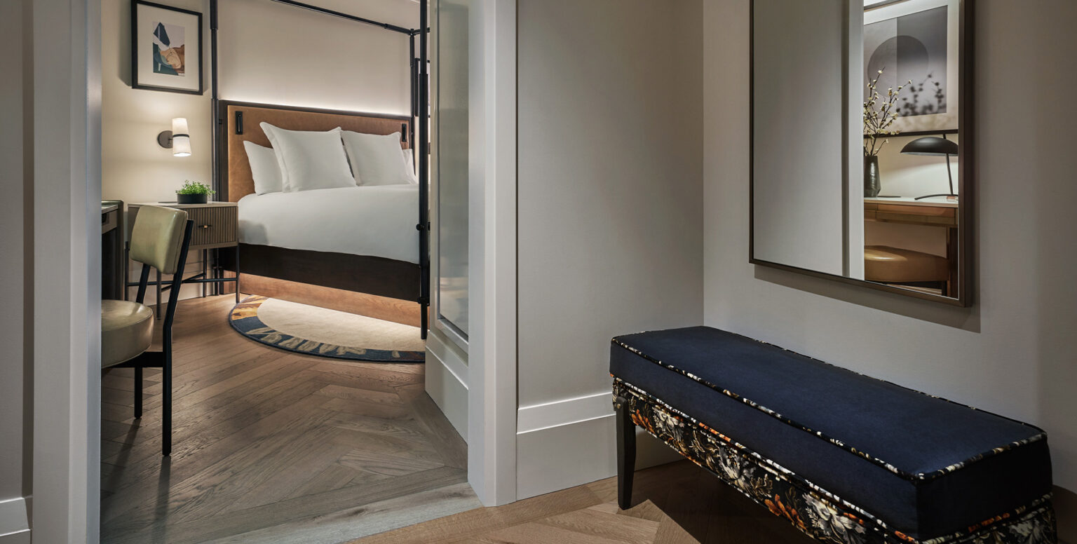A suite at Pendry Washington DC &ndash; The Wharf with a king bed and upholstered bench.
